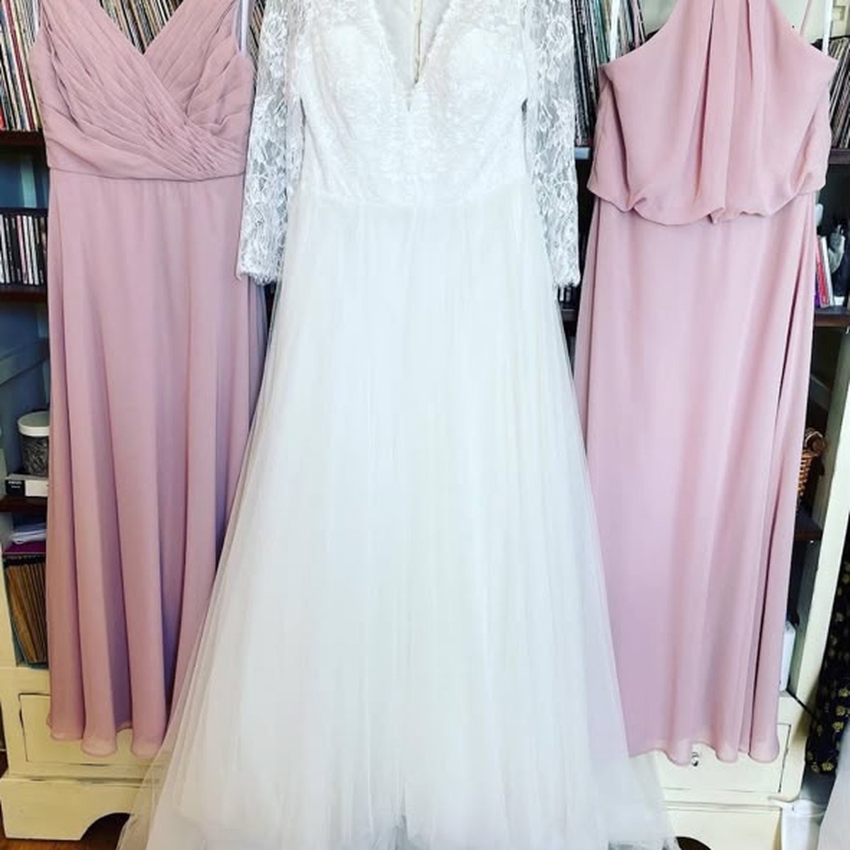 An ivory lace wedding gown between two blush-mauve bridesmaid dresses