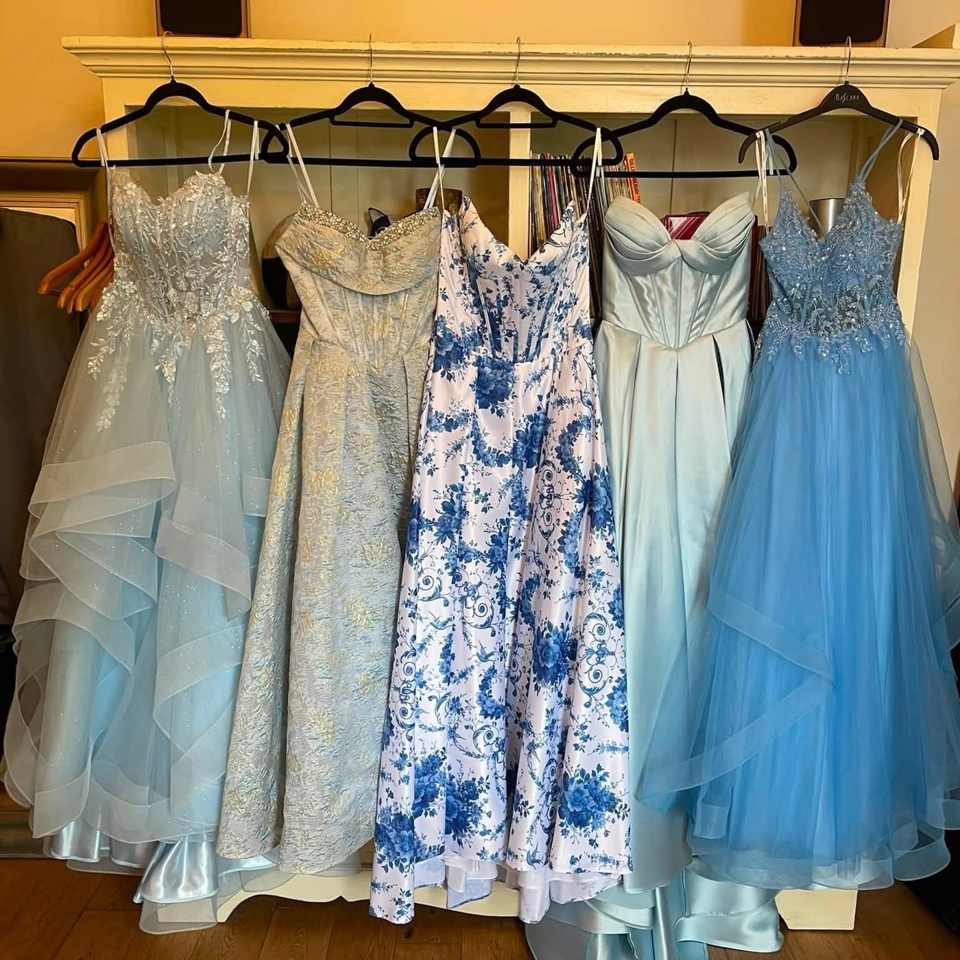 Pale blue lace, tulle and floral bridesmaid and occasion gowns on a rail